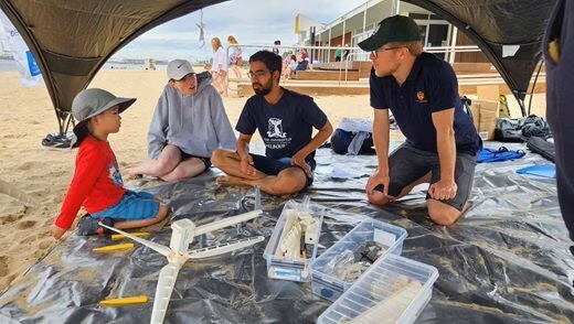 Group under a beach tent building a wind turbine model.